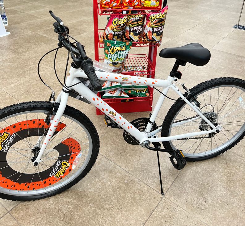 A Cheetos themed bike parked in front of a Cheetos display