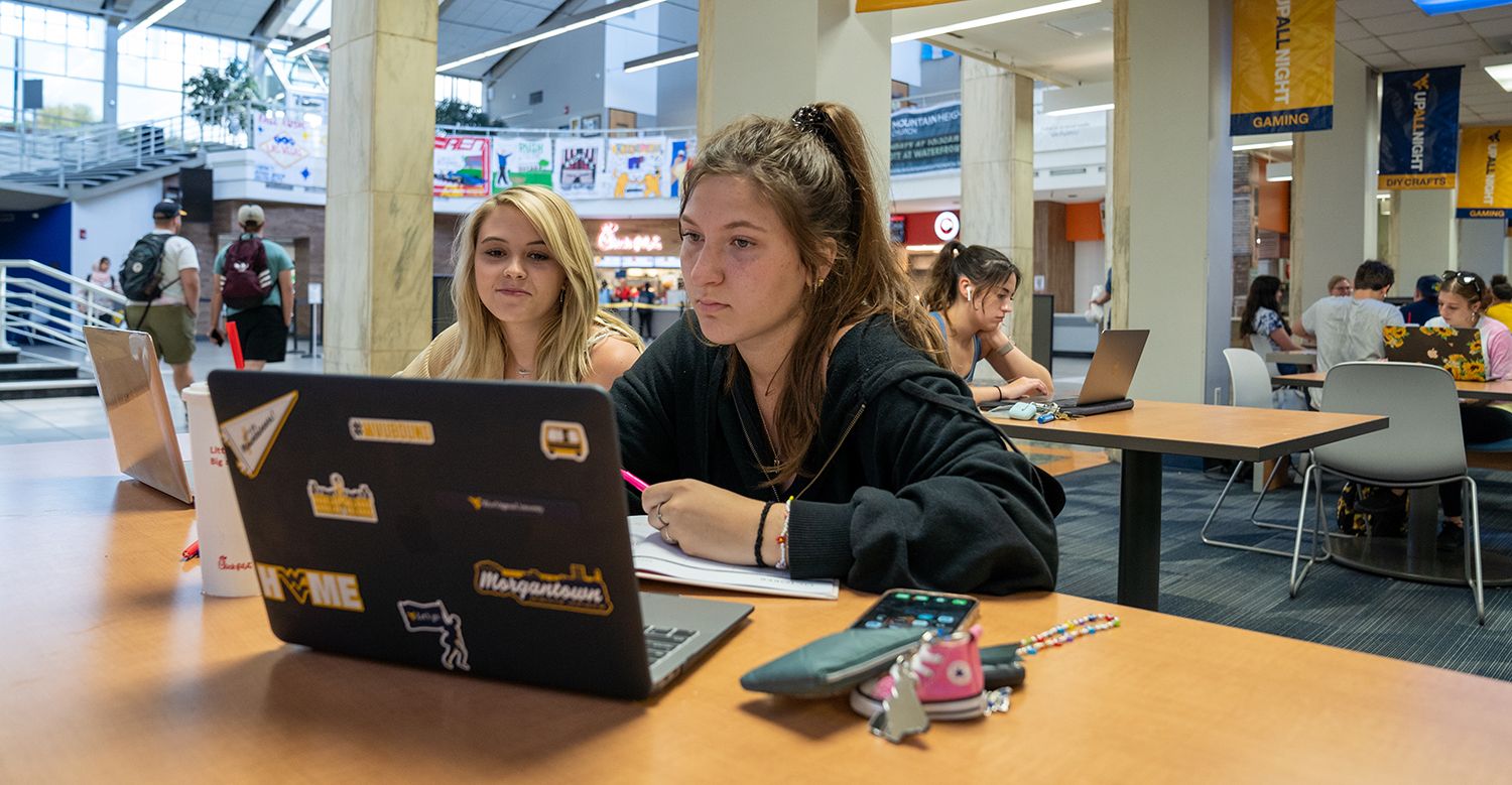 Students sit together at the Mountainlair foodcourt looking at their laptops